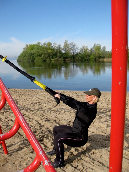 Die Frau auf dem Bild macht Kniebeugen am Strand, um ihren Beach Body zu bekommen.