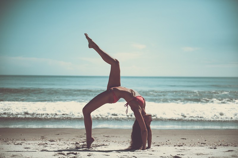 Die Frau auf dem Bild macht eine Brücke am Strand für ihren Beach Body.