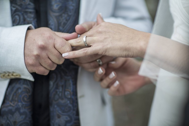 Mann hält Hand von Ehefrau bei der Hochzeit