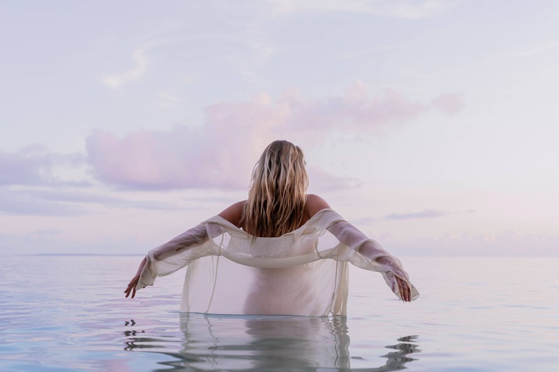 Eine Frau, die ihre Beziehung beendet hat und aus Fehlern lernen möchte. Sie steht in Freiheit im Wasser.