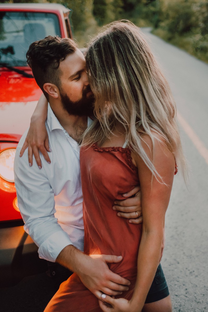 Verliebtes Paar, das vor einem Auto steht und es gerne romantisch mag