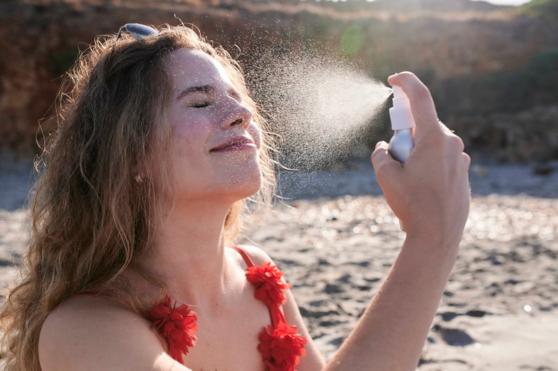 Ein Frau benutzt im Sommer als Trick ein Fixing Spray