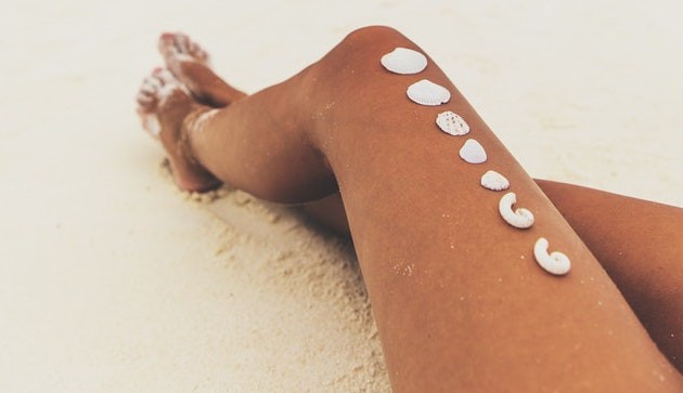 Dieses Bild zeigt eine Frau, die am Strand in der Sonne liegt und einen Sonnenbrand riskiert.