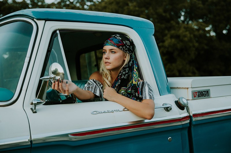 Eine Frau sitzt im Auto und es geht um Roadtrips als Aktivität im Sommer.