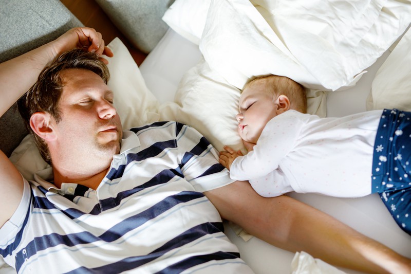 Vater und Baby schlafen in einem Bett