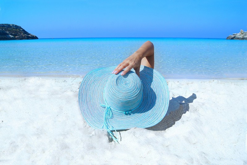 Die Frau liegt am Strand und es geht um Hautpflegetipps im Sommer