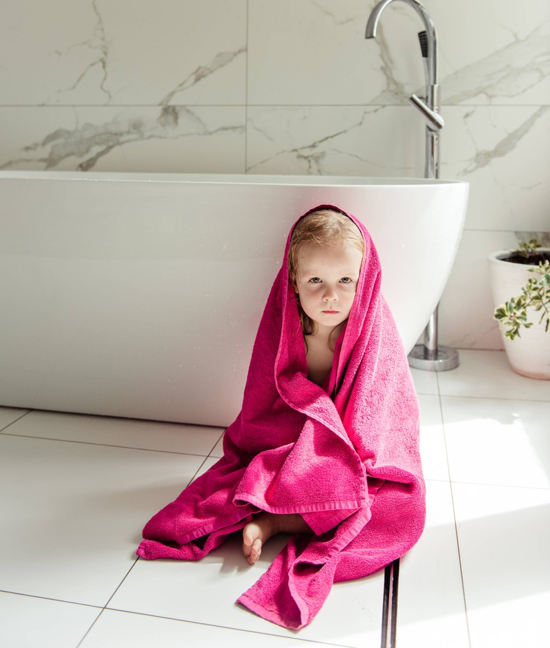 Ein Kind, das im Badezimmer aus der Dusche kommt