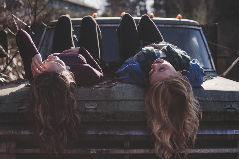 Zwei Frauen mit langen Haaren, die auf einem Auto liegen