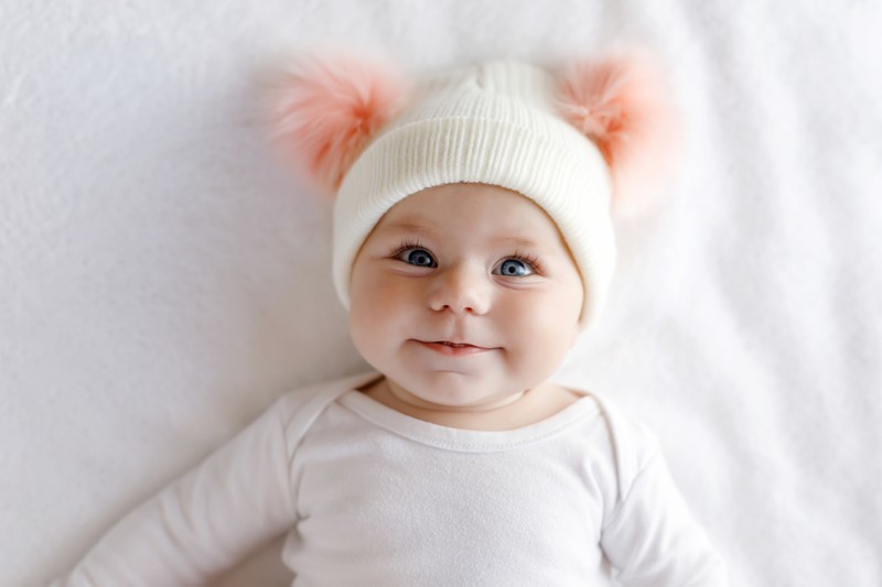 Ein Baby mit einer Puschelmütze