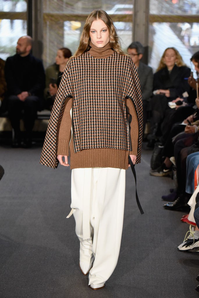 Frau mit weißer Hose und braunem Pullover