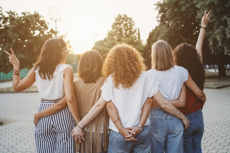 Frauen stehen Arm in Arm nebeneinander