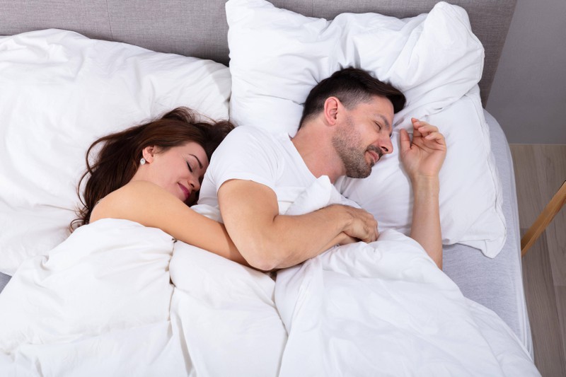 Mann und Frau liegen in Löffelchenposition nebeneinander, die für eine gute Beziehung sprechen kann
