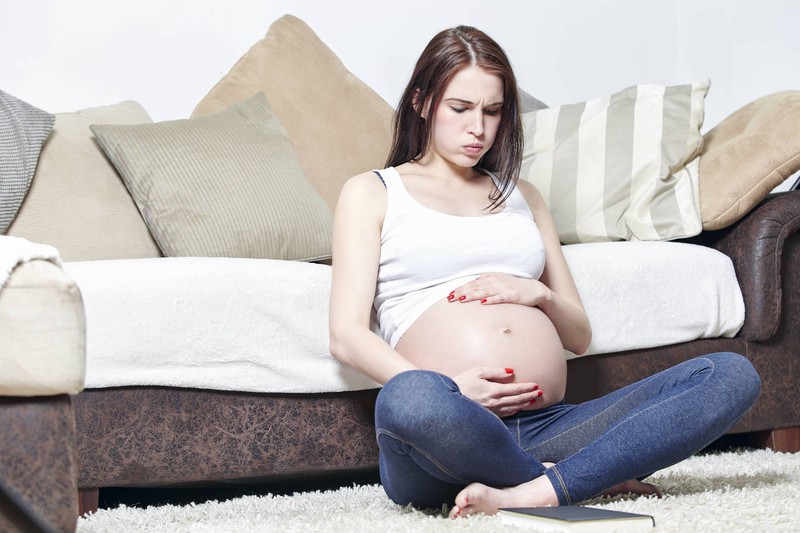 Eine schwangere Frau sitzt auf dem Boden und versucht, ruhig zu atmen