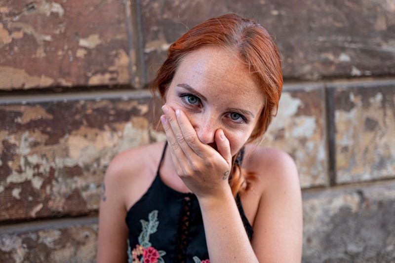 Auf dem Foto ist eine Frau, die sich an die Nase fasst, was laut Eric Standop ein Alarmzeichen für die Beziehung sein kann