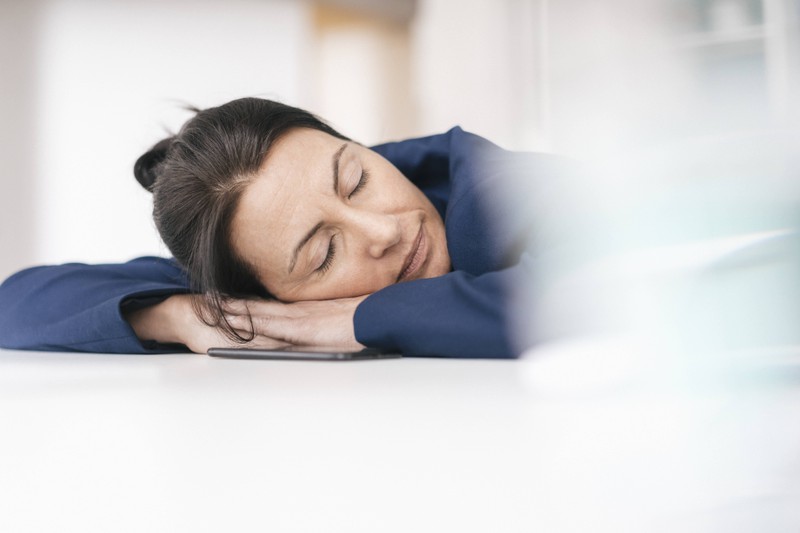 Ein Foto, das eine Frau zeigt, die im Hellen schläft und so das Risiko zur Gewichtszunahme steigert