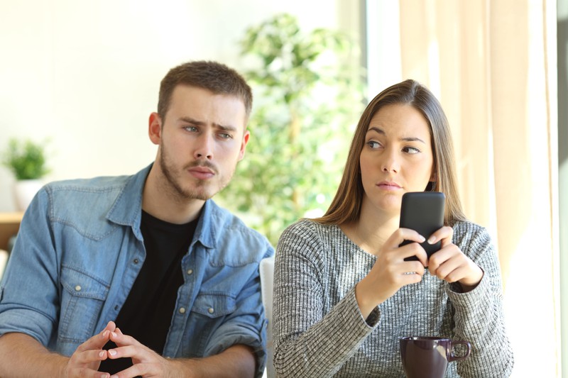 Ein Mann schaut auf das Handy seiner Frau