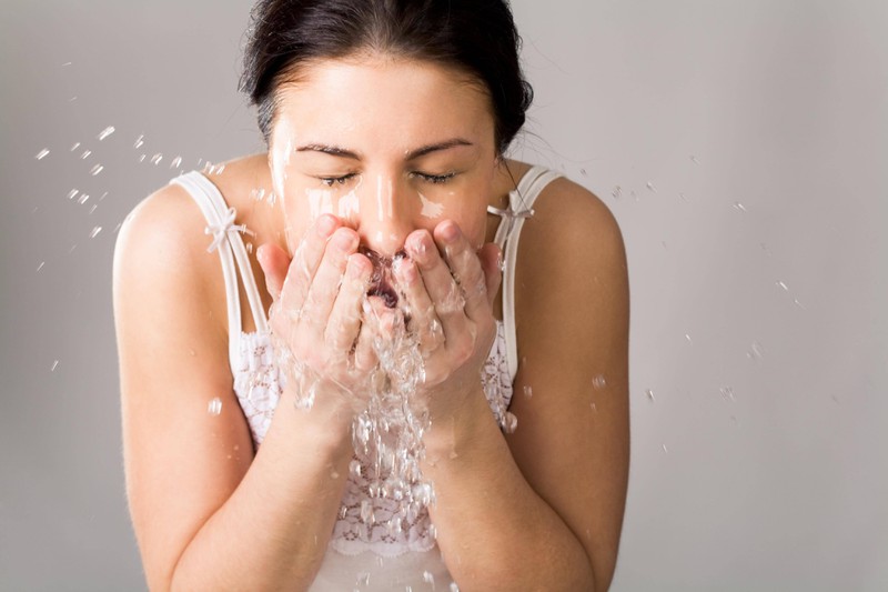 Das Foto zeigt eine Frau, die sich das Gesicht wäscht, damit sie keine Pickel bekommt