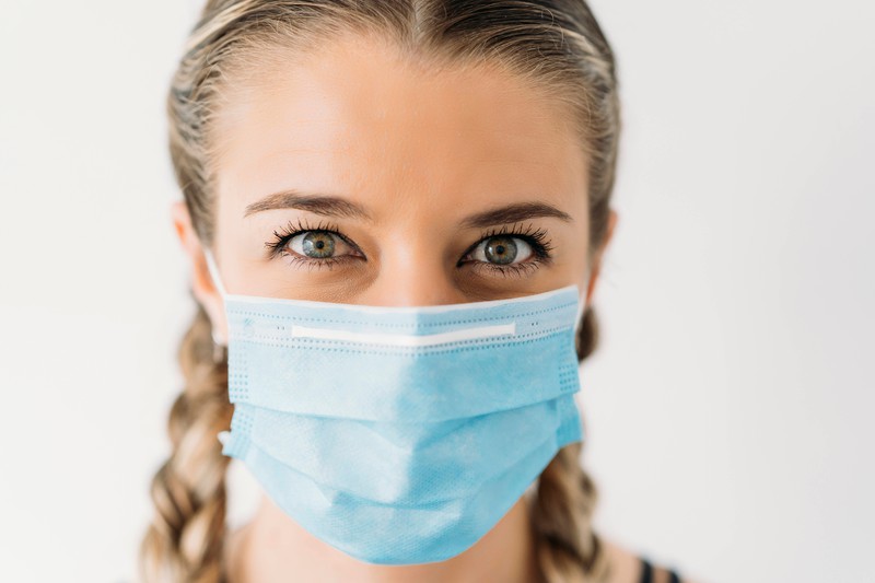 Eine Frau, die aufgrund des Coronavirus eine Maske trägt, durch die aber Pickel entstehen können
