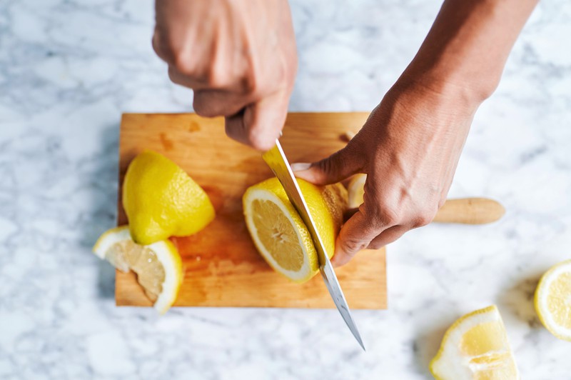 Ein Bild einer Person, die Zitronen schneidet, damit man Zitronenwasser herstellen kann