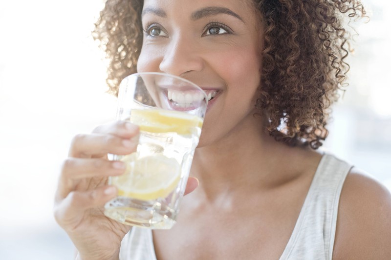 Eine Frau, die morgens ein Glas Wasser mit Zitrone trinkt, um die Verdauung zu regulieren