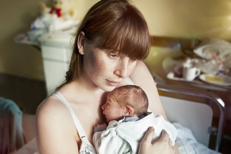Eine Mutter hält ihr neugeborenes Baby im Arm.