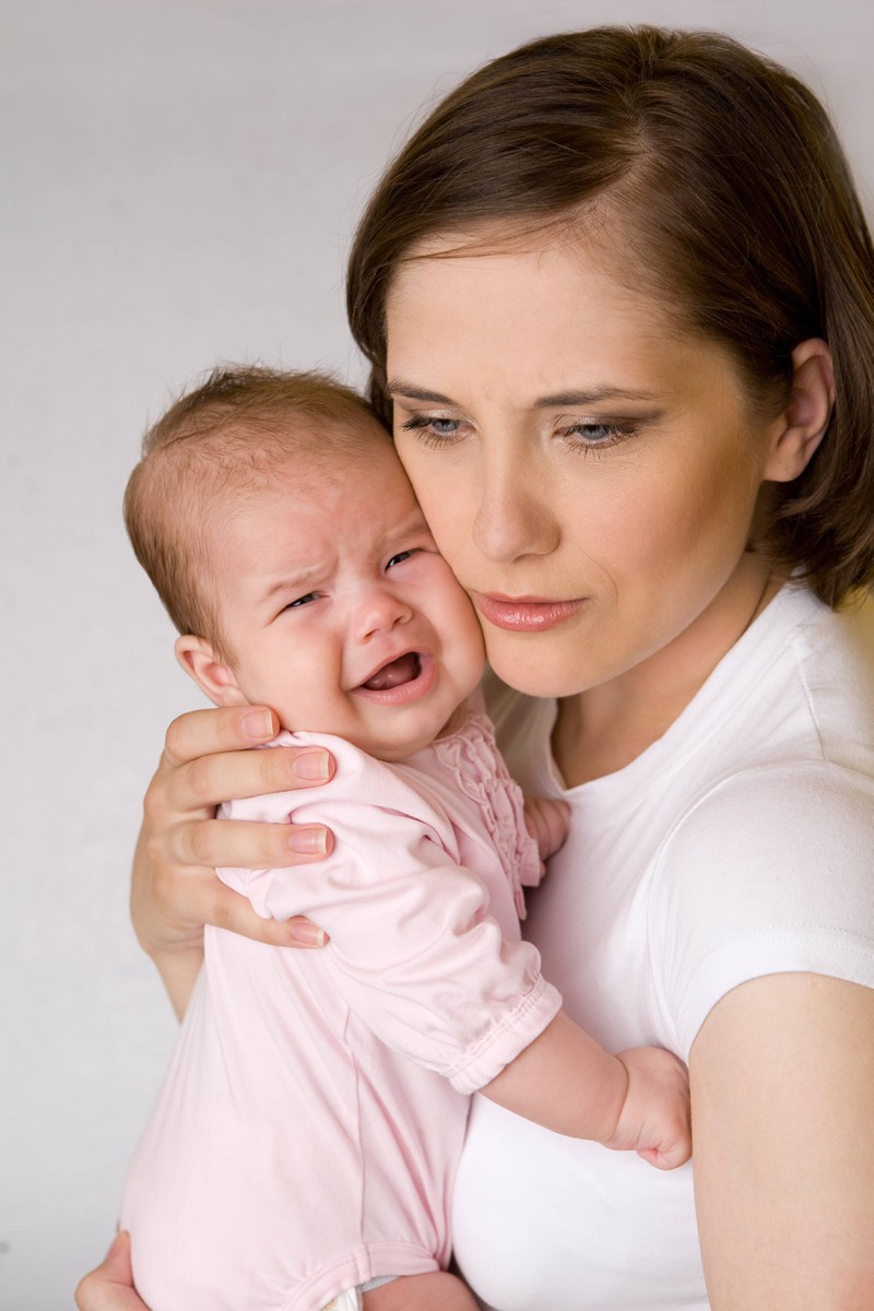 Eine Mutter mit Baby ist nach der Geburt sehr erschöpft und weint viel.